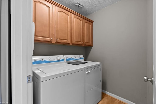 laundry area with visible vents, baseboards, cabinet space, a textured ceiling, and washer and dryer