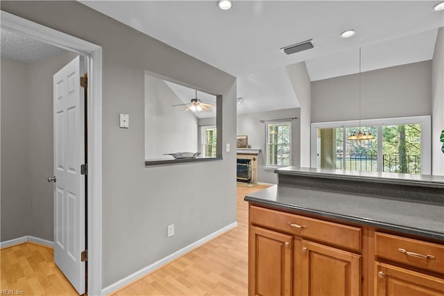 kitchen with light wood-type flooring, visible vents, baseboards, and dark countertops