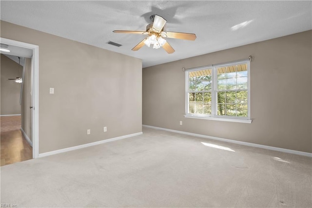 carpeted empty room with visible vents, baseboards, and ceiling fan