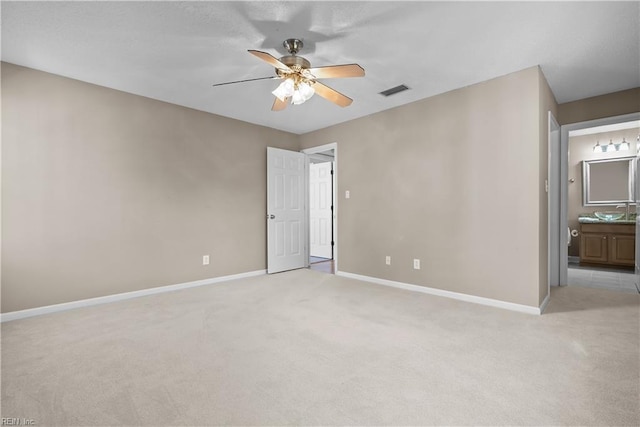 empty room featuring visible vents, light colored carpet, baseboards, and ceiling fan