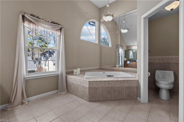 bathroom featuring a garden tub, lofted ceiling, tile patterned floors, toilet, and tile walls