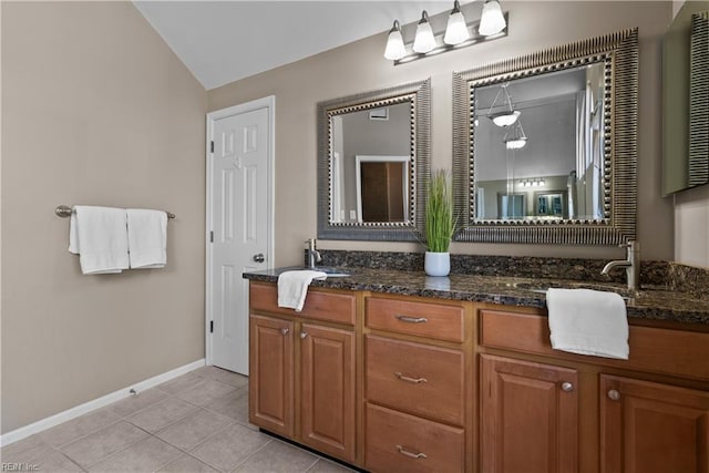 bathroom with tile patterned flooring, double vanity, vaulted ceiling, and a sink