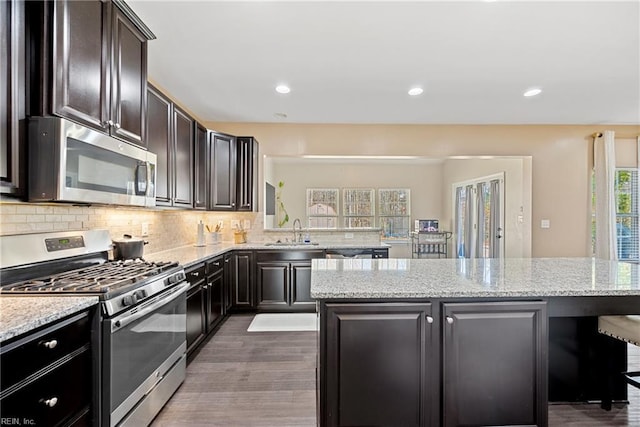 kitchen with backsplash, a kitchen island, appliances with stainless steel finishes, and a sink