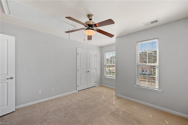 unfurnished bedroom featuring visible vents, baseboards, light colored carpet, and attic access