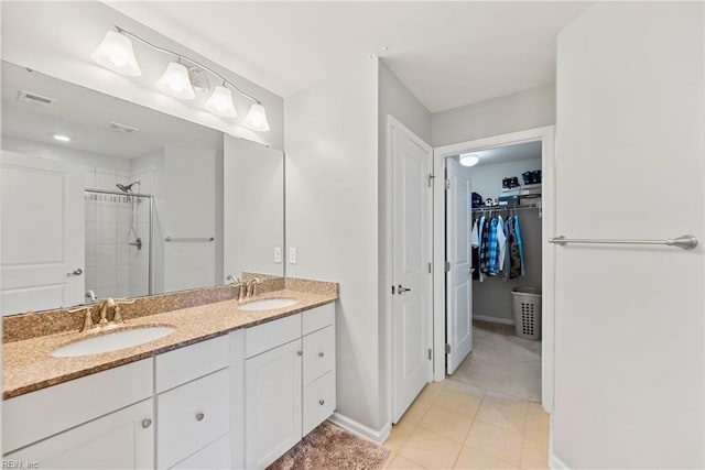 bathroom featuring double vanity, a stall shower, a spacious closet, and a sink