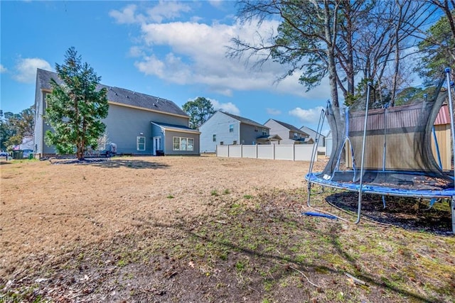 view of yard featuring a trampoline and fence