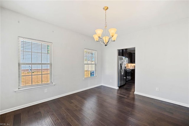 unfurnished room featuring baseboards, a notable chandelier, and dark wood finished floors