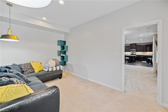 living area featuring light carpet, recessed lighting, and baseboards