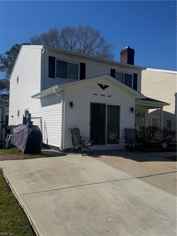 back of property with a garage, a patio, a chimney, and driveway