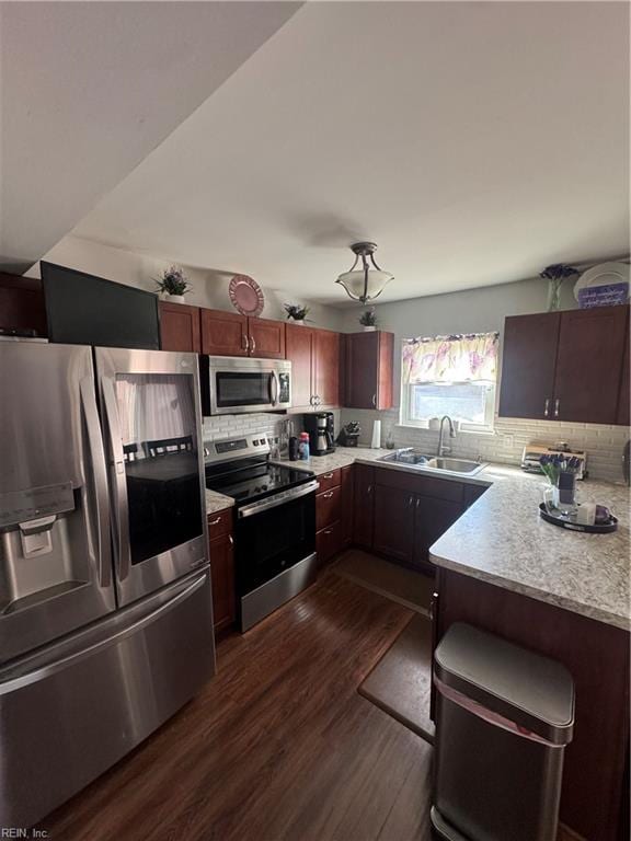 kitchen featuring stainless steel appliances, tasteful backsplash, dark wood finished floors, and light countertops