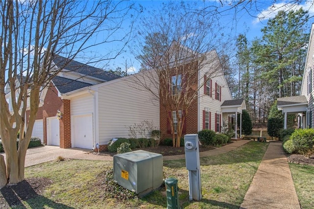 view of home's exterior with a garage, brick siding, driveway, and a yard