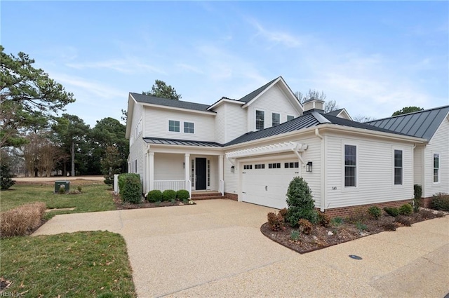 traditional-style house featuring a standing seam roof, an attached garage, covered porch, and driveway