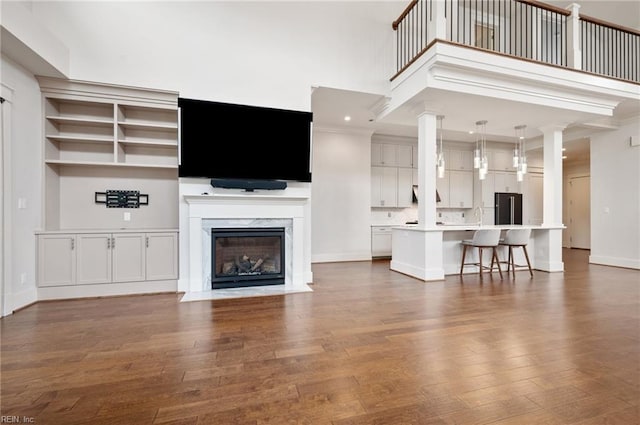 unfurnished living room featuring a towering ceiling, baseboards, wood finished floors, and a fireplace