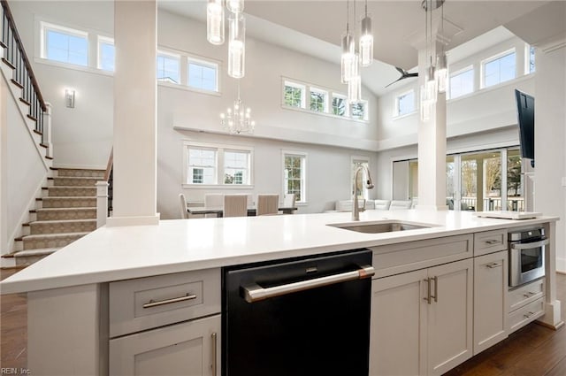 kitchen with oven, a sink, light countertops, dishwasher, and a chandelier