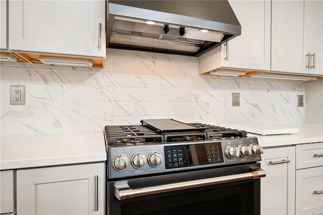 kitchen featuring gas range, tasteful backsplash, exhaust hood, and light countertops