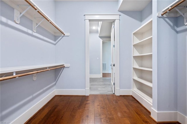 spacious closet featuring visible vents and dark wood-type flooring