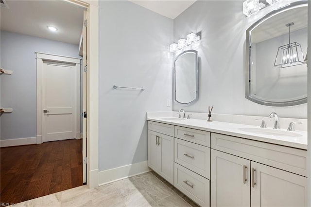 full bathroom with double vanity, baseboards, and a sink