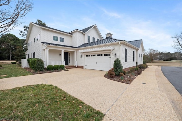 view of front of house featuring driveway, a standing seam roof, covered porch, an attached garage, and metal roof