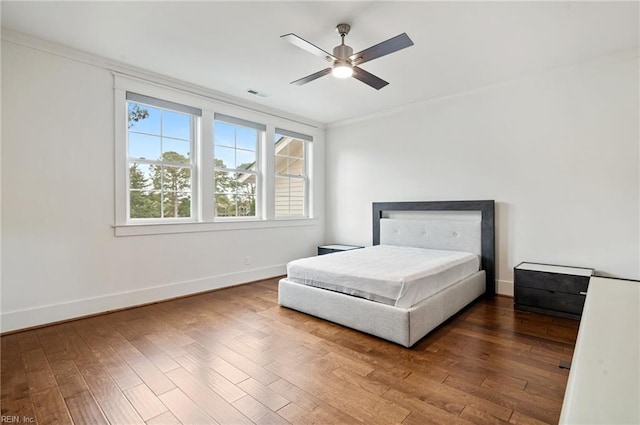 bedroom featuring visible vents, crown molding, ceiling fan, baseboards, and wood finished floors