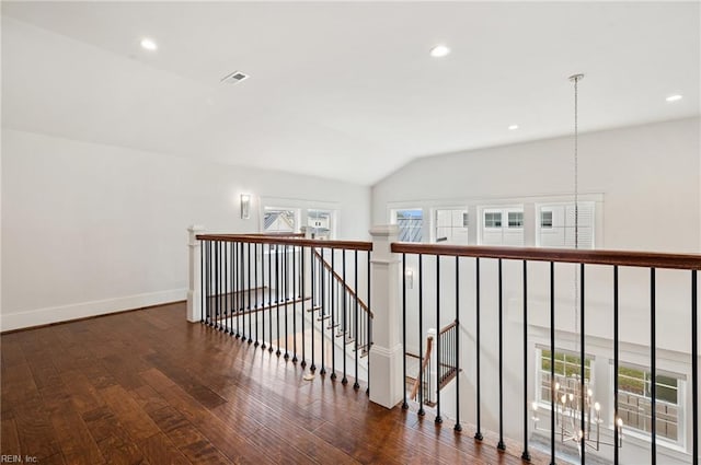 corridor with visible vents, an upstairs landing, baseboards, wood-type flooring, and lofted ceiling