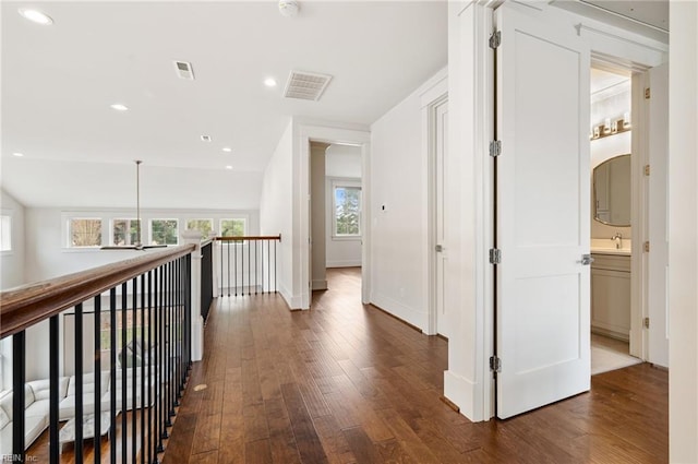 hall featuring visible vents, a sink, dark wood-style floors, recessed lighting, and baseboards