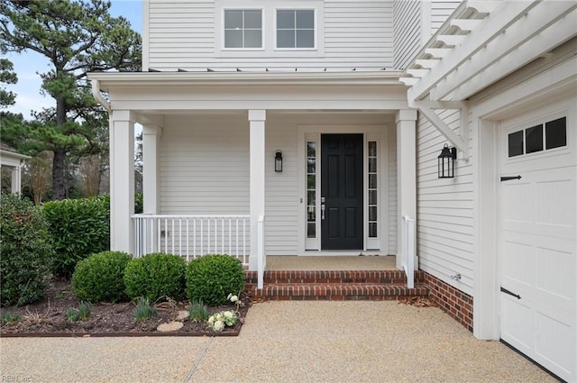 view of exterior entry with a garage and a porch