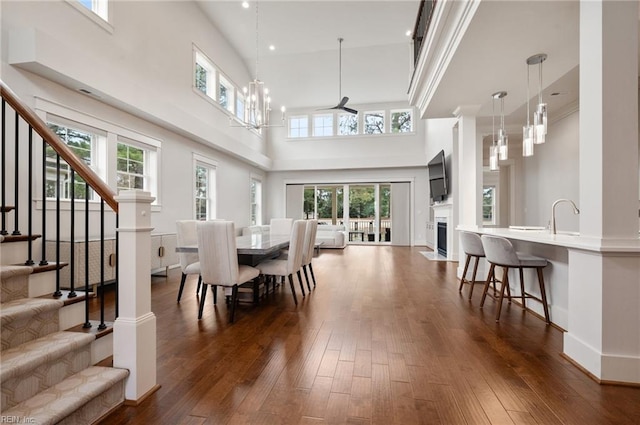 dining area featuring dark wood-type flooring, baseboards, stairway, a fireplace with flush hearth, and a notable chandelier