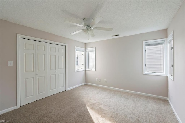 unfurnished bedroom with baseboards, visible vents, a closet, a textured ceiling, and carpet flooring