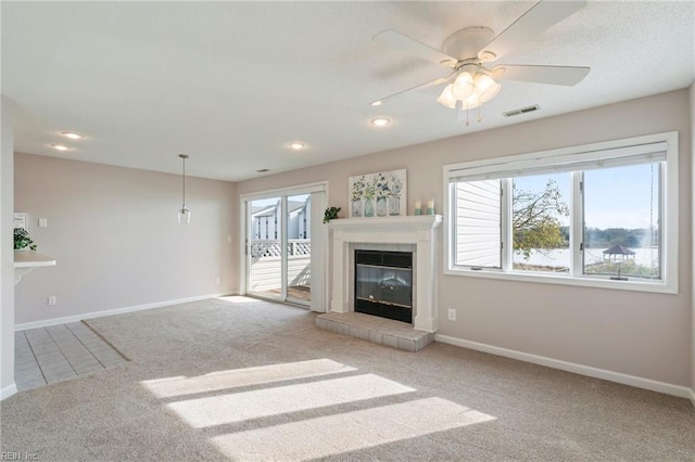 unfurnished living room featuring baseboards, visible vents, carpet floors, recessed lighting, and a tiled fireplace