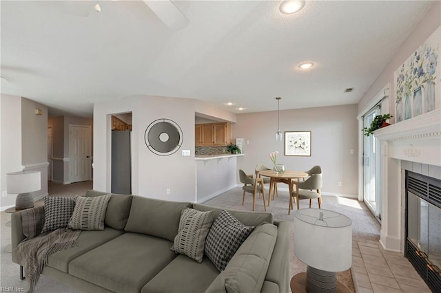 living room with light tile patterned floors, visible vents, baseboards, recessed lighting, and a tile fireplace