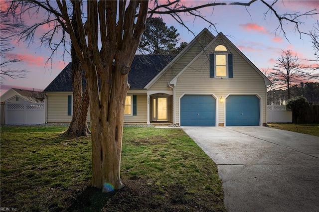 traditional-style home featuring a lawn, concrete driveway, a garage, and fence