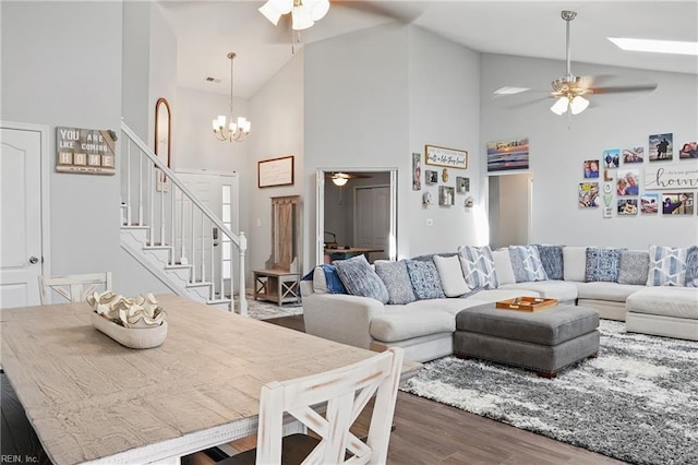 living room with ceiling fan with notable chandelier, stairs, and wood finished floors