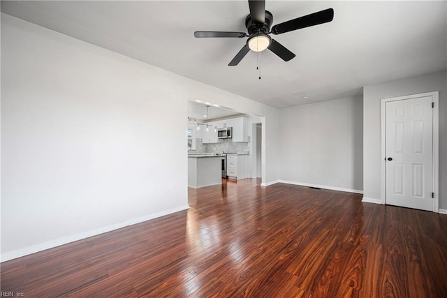 unfurnished living room featuring baseboards, dark wood-style floors, and a ceiling fan