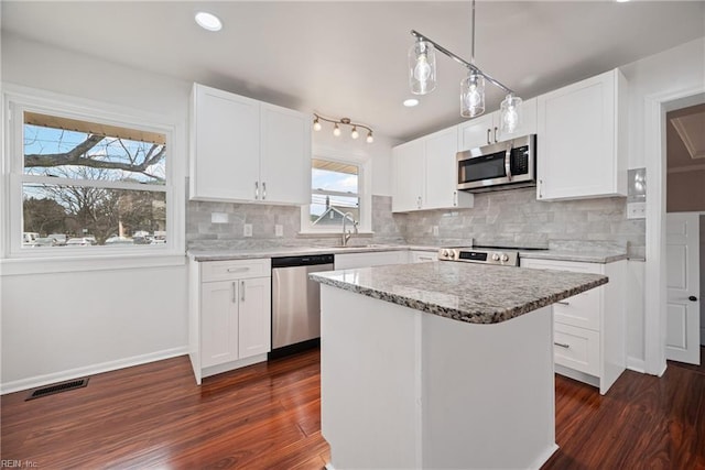 kitchen with visible vents, dark wood finished floors, a sink, decorative backsplash, and appliances with stainless steel finishes