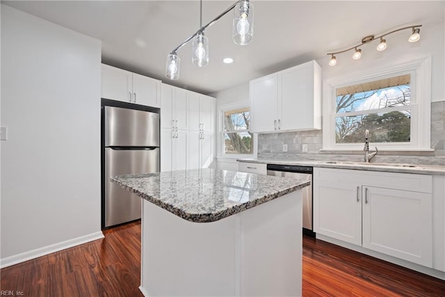 kitchen featuring a sink, light stone counters, tasteful backsplash, white cabinetry, and stainless steel appliances