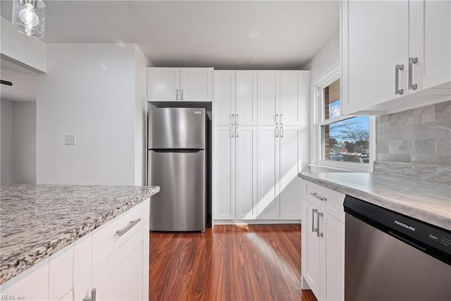 kitchen featuring light stone countertops, dark wood finished floors, decorative backsplash, appliances with stainless steel finishes, and white cabinetry