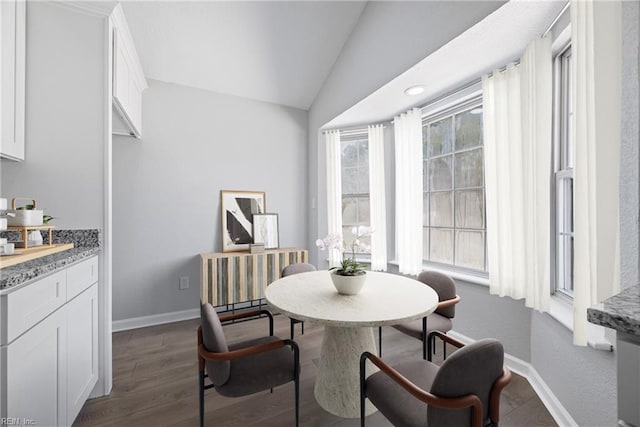 dining area featuring dark wood finished floors, baseboards, and lofted ceiling