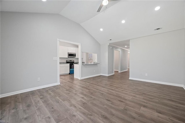 unfurnished living room featuring visible vents, a ceiling fan, a sink, wood finished floors, and baseboards