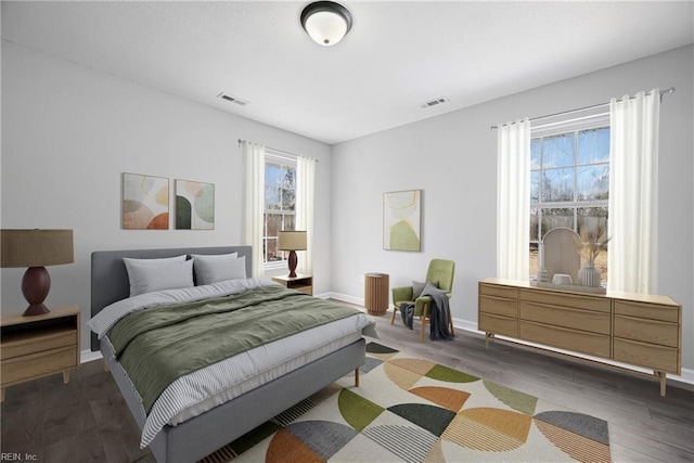 bedroom with visible vents, baseboards, and wood finished floors