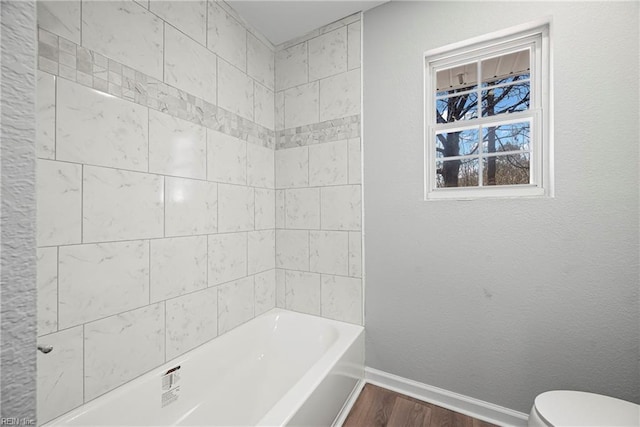 full bathroom featuring a textured wall, toilet, baseboards, and wood finished floors