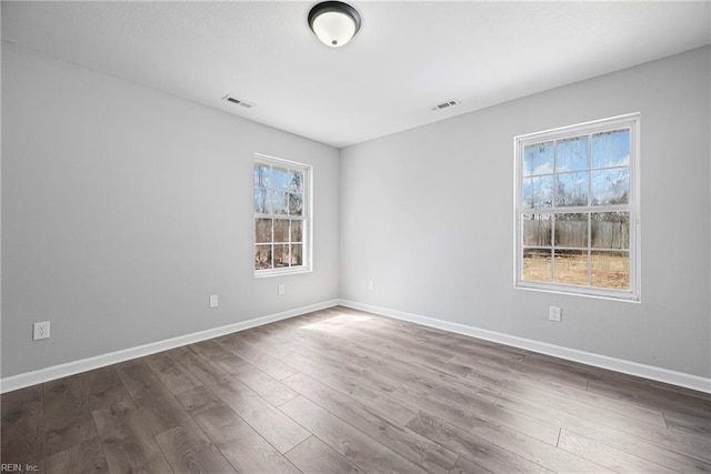 spare room featuring dark wood-style floors, visible vents, and baseboards