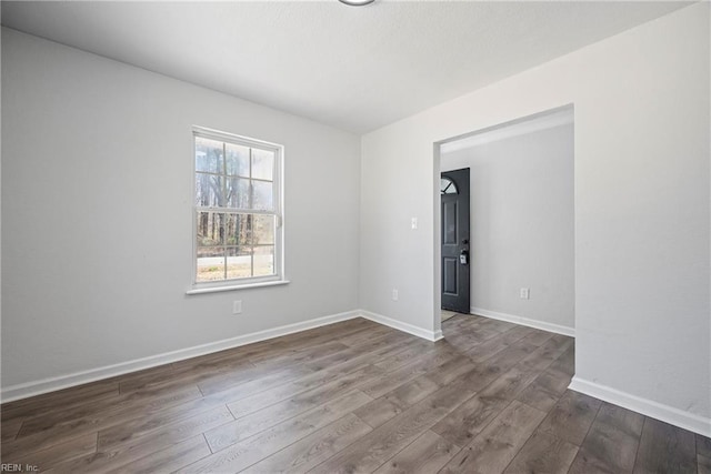 empty room with dark wood finished floors and baseboards