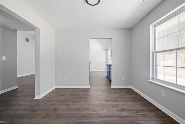 spare room with visible vents, dark wood-type flooring, and baseboards