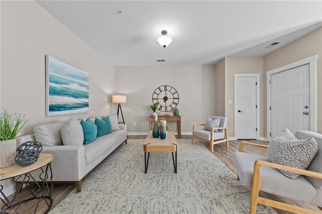 living room featuring visible vents, baseboards, and light wood-style flooring