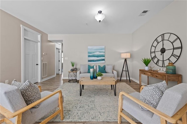 living room featuring visible vents, baseboards, and wood finished floors