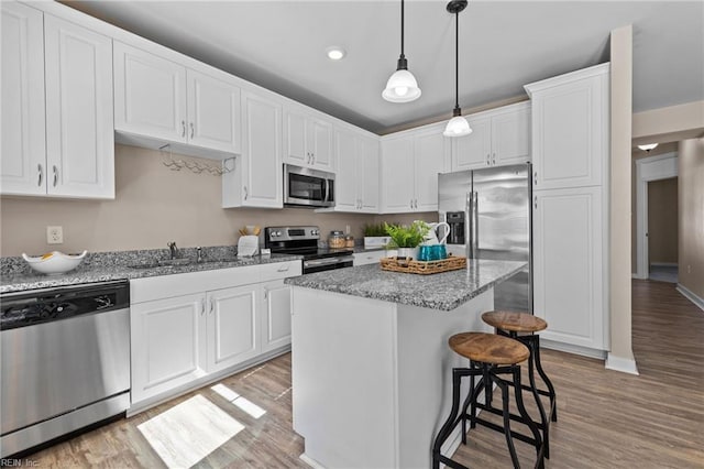 kitchen with a breakfast bar area, light wood-style flooring, appliances with stainless steel finishes, white cabinets, and a sink