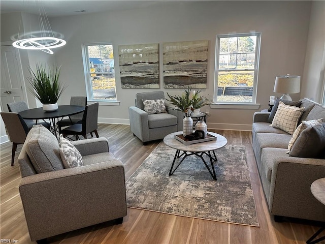 living area with a notable chandelier, baseboards, and wood finished floors