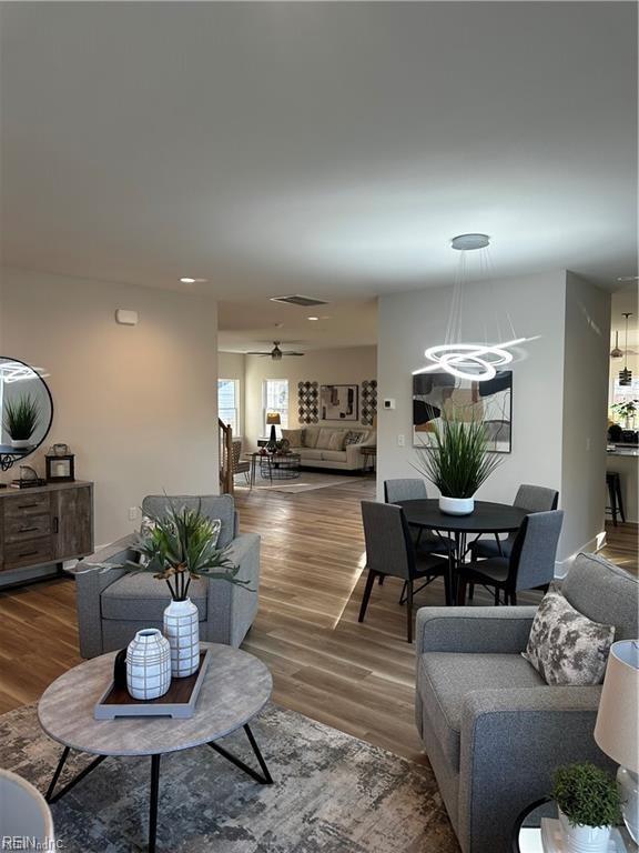 living area with visible vents, ceiling fan with notable chandelier, and wood finished floors