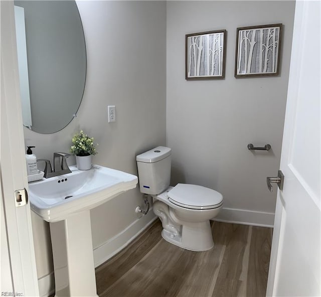 half bathroom featuring baseboards, toilet, and wood finished floors