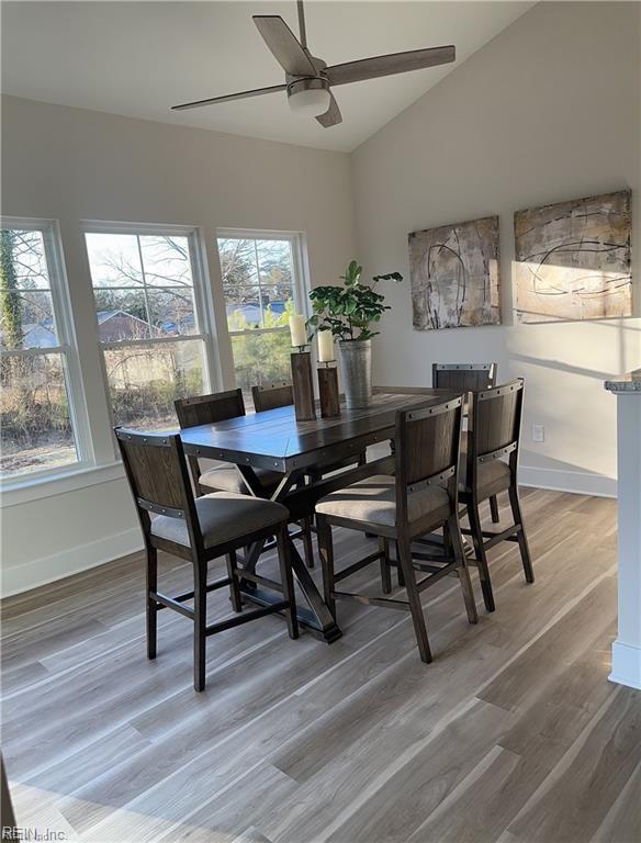 dining space featuring baseboards, lofted ceiling, ceiling fan, and light wood finished floors